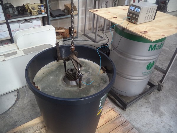 The drilling motor soaking in the electrolytic bath at 4 amps