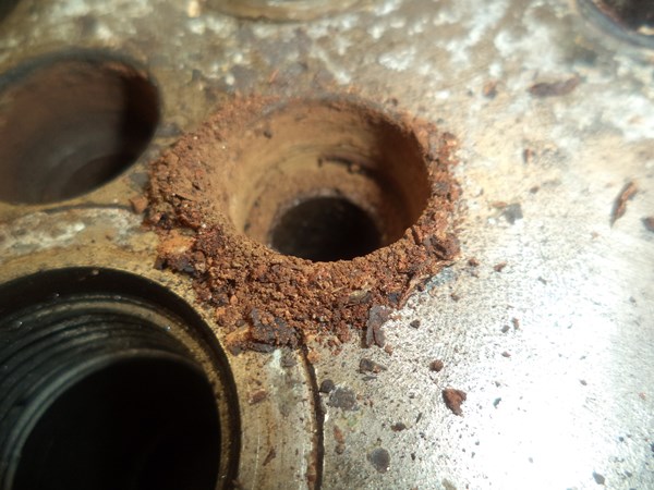 The rust crawls out of the counter-bore like dry sand