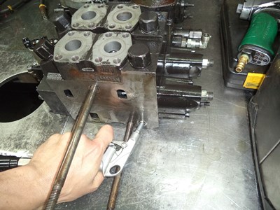 Blowing compressed air into a shuttle valve to check for obstruction